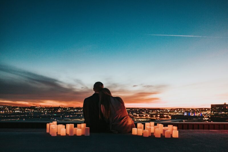 A couple embracing on a balcony overlooking a city, symbolizing the intersection of connection, intimacy, and strategic understanding in both love and business.